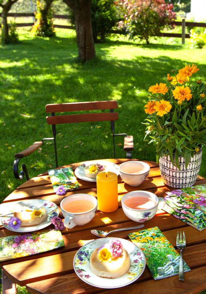 Ein bunt dekorierter Gartentisch steht im Grünen und die Gäste können kommen.