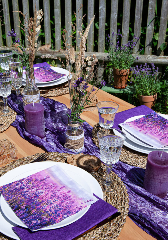 Ein in Lilatönen gedeckter Tisch bringt Farbe ins Spiel. Die passende Serviette ist mit Lavendel bedruckt.