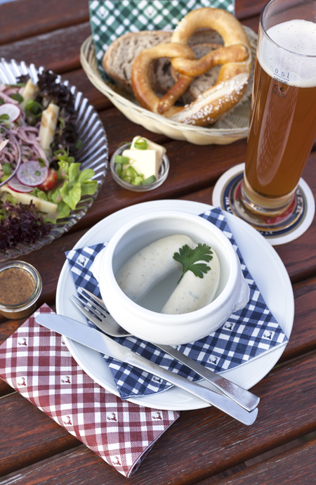 Alles ist vorbereitet für einen bayrischen Abend, Weißwurst, Brezn und Wurstsalat. Die passende Serviette im Karolook in drei verschiedenen Farben gibt dem Bild die passende Stimmung.