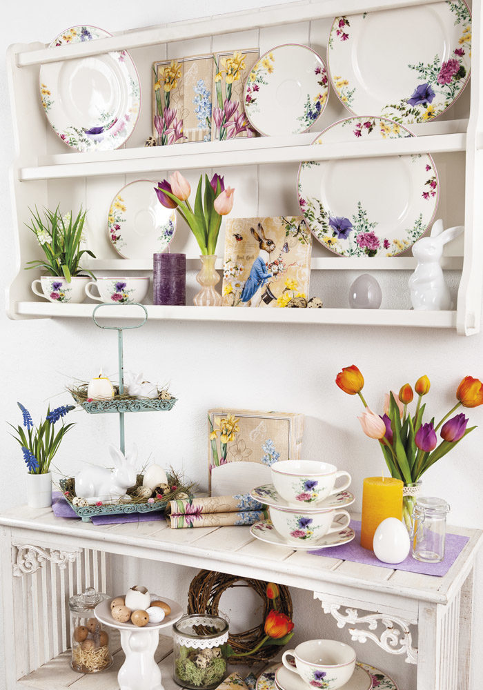 Ein Küchenregal mit buntem Geschirr und passenden Servietten mit Osterhase sind zu sehen.
