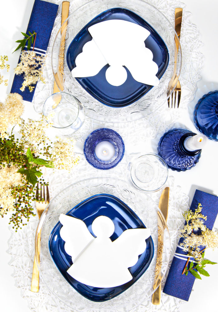 Eine weiße Serviette als Engel gestanzt und gefaltet, wirken auf den blauen Tellern besonderes elegant.