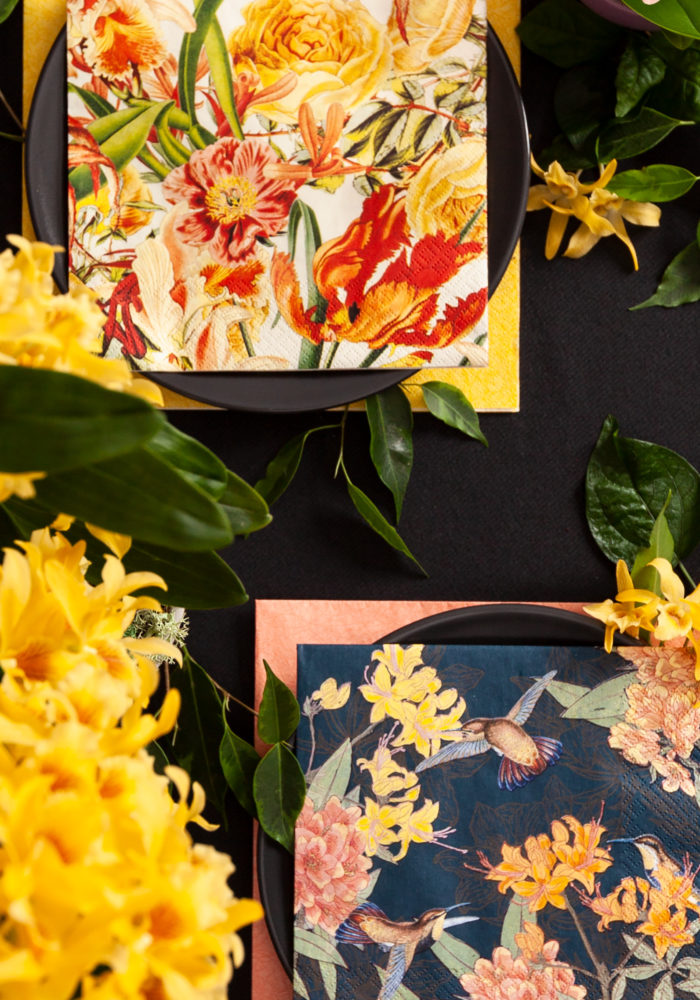 Tropische Blüten sind auf Servietten gedruckt und sind ein Blickfang auf dem gedeckten Tisch.